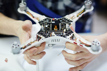 Closeup shot of male hands holding opened drone showing main circuit board and micro controller...