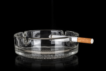 Glass ashtray with cigarette isolated on black