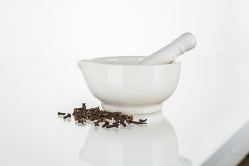 White ceramic mortar with clove isolated on white