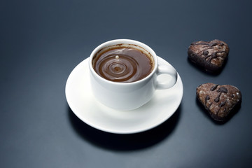 white cup of black coffee with biscuits on a dark background