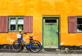 Fototapeta na wymiar Blue Bike on Yellow Wall Next to Green Door