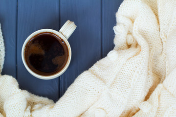 Cup of black coffee, white knitted plaid, on grey wooden backgro