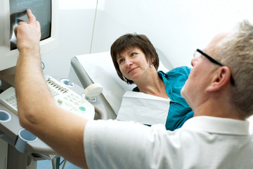 Befundung am Sonographie Gerät mit Arzt und Patientin in der Praxis
