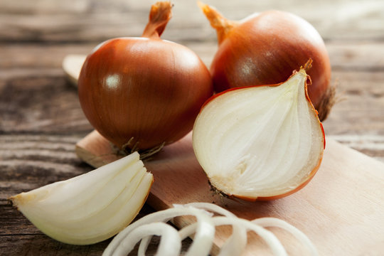 A sliced onion and fresh onions on cutting board