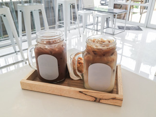 Glasses of iced latte milk coffee on wooden tray and white background, selective blur background
