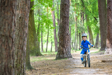 Happy kid boy of 4 years having fun in autumn or summer forest with a bicycle on beautiful fall spring day. Active child making sports. Safety, , leisure kids concept. © pahis