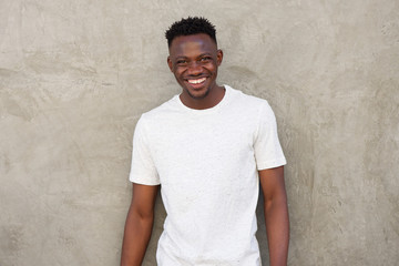 happy young african american man smiling by wall