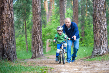 Happy cute blond kid boy having fun his first bike on sunny summer day, outdoors.  child making sports. Active leisure for children.  wear safety helmet.  is smiling and cicling