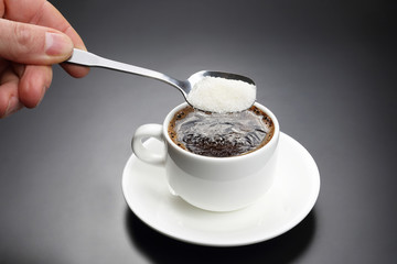 white cup with black coffee and spoon with sugar