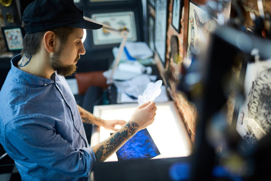 Young man looking at just drawn ornament for tattoo