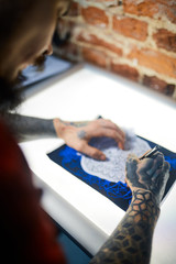 Obraz premium Hands of man with tattooes drawing ornament with pen