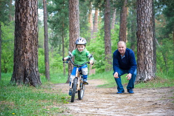 Happy cute blond kid boy having fun his first bike on sunny summ