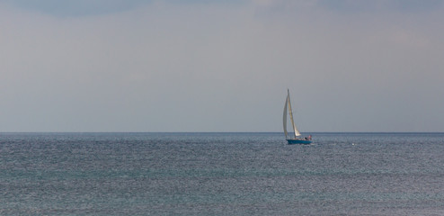 Sailboat with blue hull and main sail and jib out on ocean