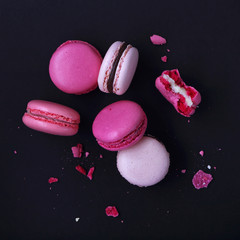 Macaroons on dark background, colorful french cookies macarons. The broken macarons with crumbs. Gift for Valentine's Day and 8 March International Women's Day