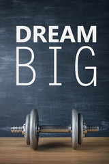 metal barbell on dark gray background and motivation text dream big