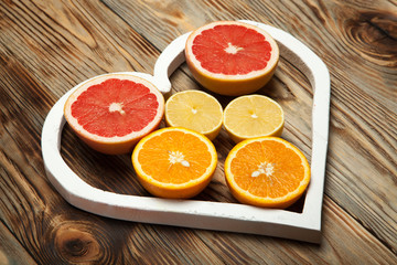 Fototapeta na wymiar Citrus fruit in a heart on wooden background
