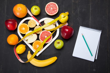 Diet, fruits and centimeter on a black background