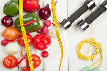 Sport and diet. Healthy lifestyle. Vegetables, dumbbells. Peppers, tomatoes, garlic, onions radishes on a white background