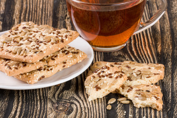 crispy bread with seeds of sunflower, flax and sesame seeds with a cup of tea on a dark wooden background