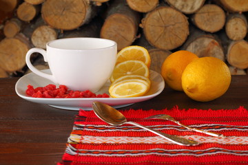 Чайные аксессуары и лимон с сушенной вишней на фоне березовых дров.