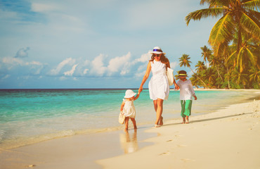 mother with little son and daughter walk on beach