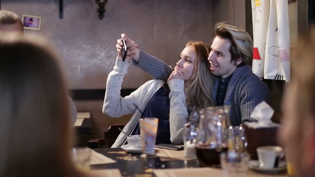 Hipster couple doing selfie with cellphone in cafe