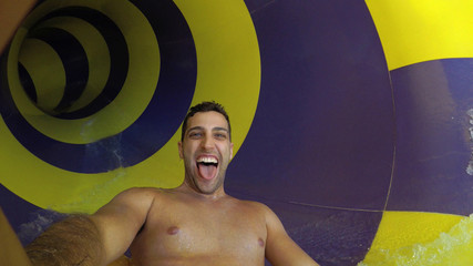 Man having fun and sliding down in a water slide