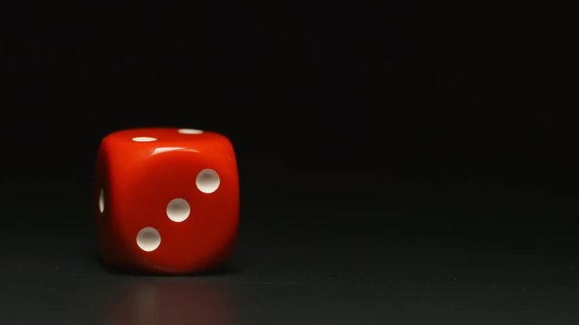 SLOW MOTION: Red playing cube rolls and stop