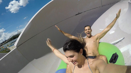 Couple having fun and sliding down in a water slide