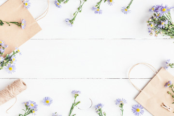 Flowers composition. Gifts and wildflowers on wooden white background. Flat lay, top view
