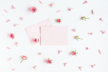 Paper blank and pink flowers on white background. Mockup with flowers. Flat lay, top view