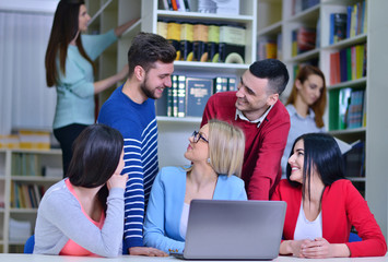Group Of Students Working Together In Library With Teacher