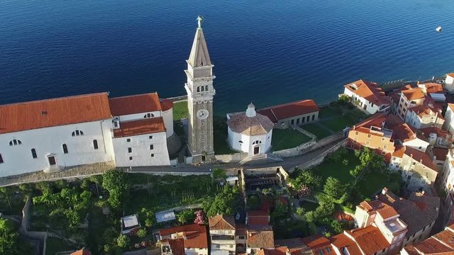 Flight over old city Piran in Slovenia, aerial bird's eye view with old houses, St. George's Parish Church and the sea. 