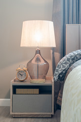 classic lamp style with alarm clock on table side in cozy bedroo