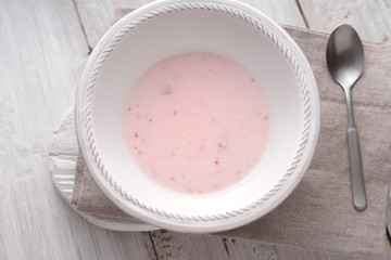 Fruit yogurt in the white plate on the white wooden table  top view