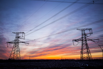 Fototapeta premium The silhouette of the evening electricity transmission pylon