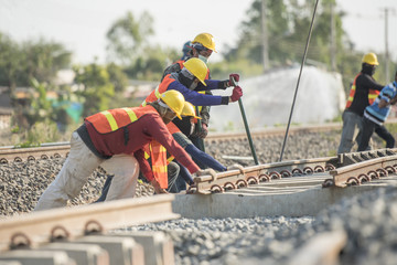 Construction team work in standard construction safety uniform installing precast concrete railway...