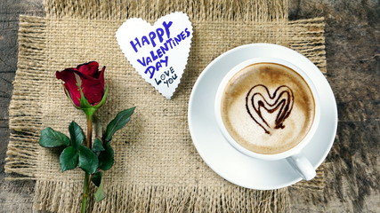 Cappuccino coffee with chocolate hearts. A cup of latte, cappuccino or espresso coffee with milk put on a wood table with dark roasting coffee beans. Drawing the foam milk on top.