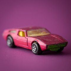Fuchsia toy sports car on fuchsia background