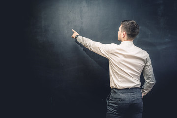 Man in suit pointing something on chalkboard,back view,isolated.Copyspace blank.Teacher writing on black board