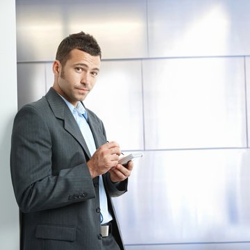 Annoyed young businessman in suit with tablet