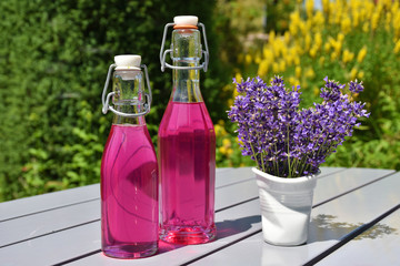 Homemade lavender syrup in glass bottles and a bouquet of lavender blossoms