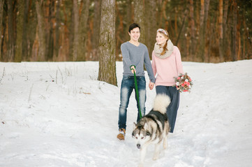 Fototapeta na wymiar Outdoor happy couple in love posing with dog in cold winter weather. Young boy and girl having fun outdoor. Boho