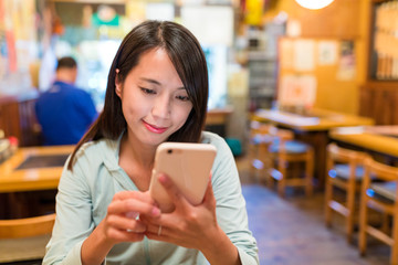 Woman looking at mobile phone in japanese restaurant