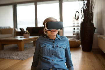 Senior woman wearing virtual reality goggles at home