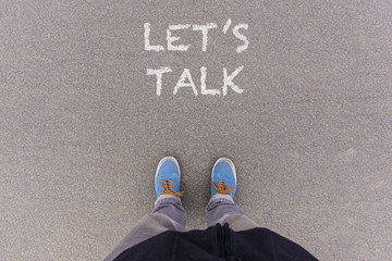 Let us talk text on asphalt ground, feet and shoes on floor