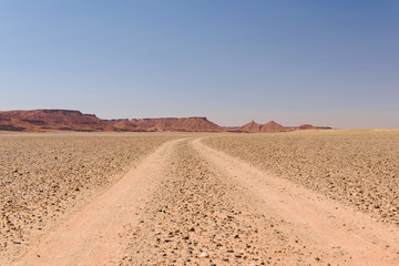 Fototapeta na wymiar Dusty off-road track leading to the horizon, Morocco