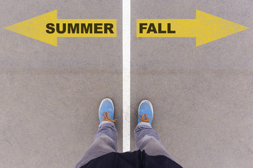 Summer and fall text arrows on asphalt ground, feet and shoes on