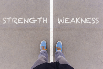 Strength and weakness text on asphalt ground, feet and shoes on