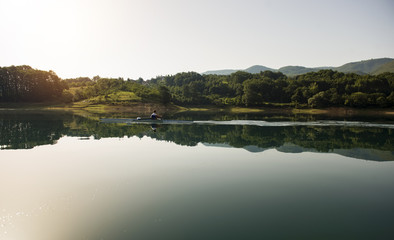 A Young single scull rowing competitor paddles on the tranquil lake
